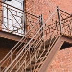 Metal steps outside the old brick house. Staircase with emergency exit. Fire safety.